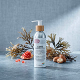 A silver pump bottle labeled “Core Oily Sensitive Everyday Moisturiser” by Biotaderm rests on a gray surface, surrounded by seaweed, pomegranate seeds, and argan nuts—showcasing the nourishing plant oils inside this body moisturiser specially formulated for oily sensitive skin.