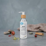A silver pump bottle labeled “Biotaderm Deep Balanced Rich Moisturiser” stands on a gray surface with dried botanicals and a beige cloth in the background, highlighting its rich texture and nourishing blend of five premium plant oils.