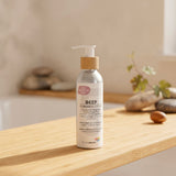 A bottle of Biotaderm Deep Oily Sensitive Rich Moisturiser with a pump dispenser sits on a wooden surface, surrounded by stones and a plant in the background. Formulated with nourishing plant oils, this moisturiser is perfect for those with oily sensitive skin who desire balanced hydration.